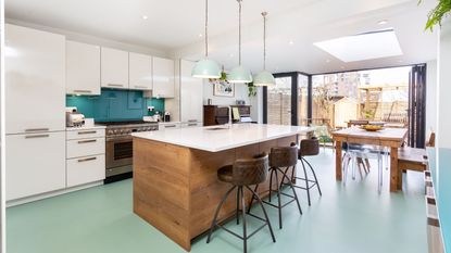 Kitchen island and pink cabinets with white countertop in front of bay windows