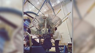 A person stands under the pioneer 10 spacecraft during the final assembly.