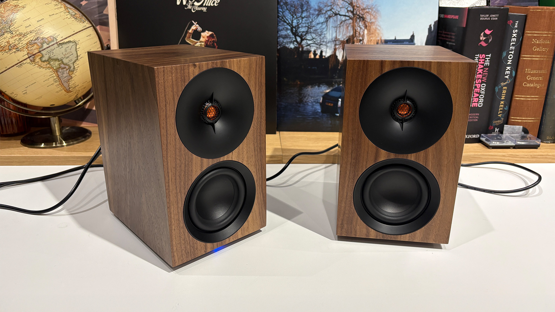 Cambridge Audio L/R S desktop speakers on white surface in front of busy bookcase