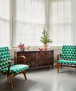 A white living room with green chairs and a wooden table with festive decor on it