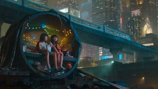 Two kids sit in a futuristic pod with a city skyline behind them