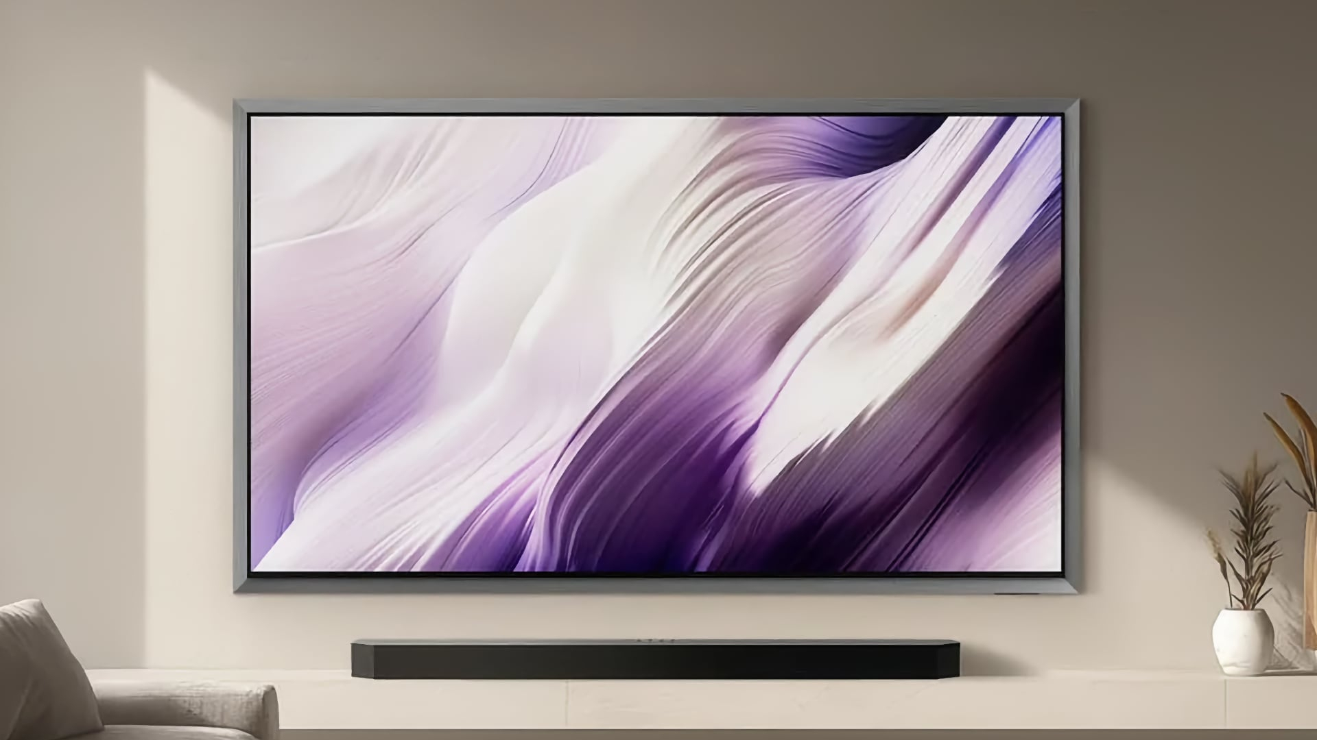 The Samsung S99H OLED TV displaying colorful, abstract imagery while being wall-mounted in a modern living room above a soundbar
