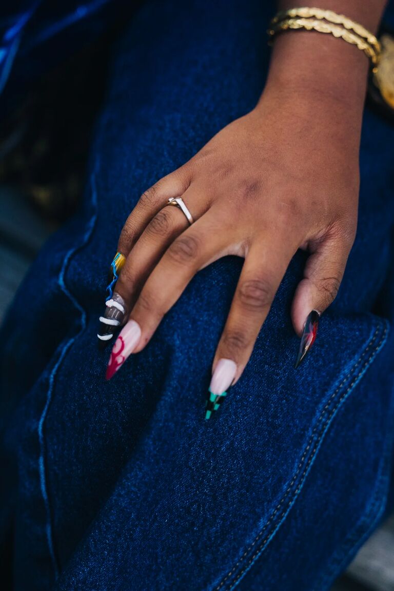 a woman with brown skin and different nail designs wearing silver rings