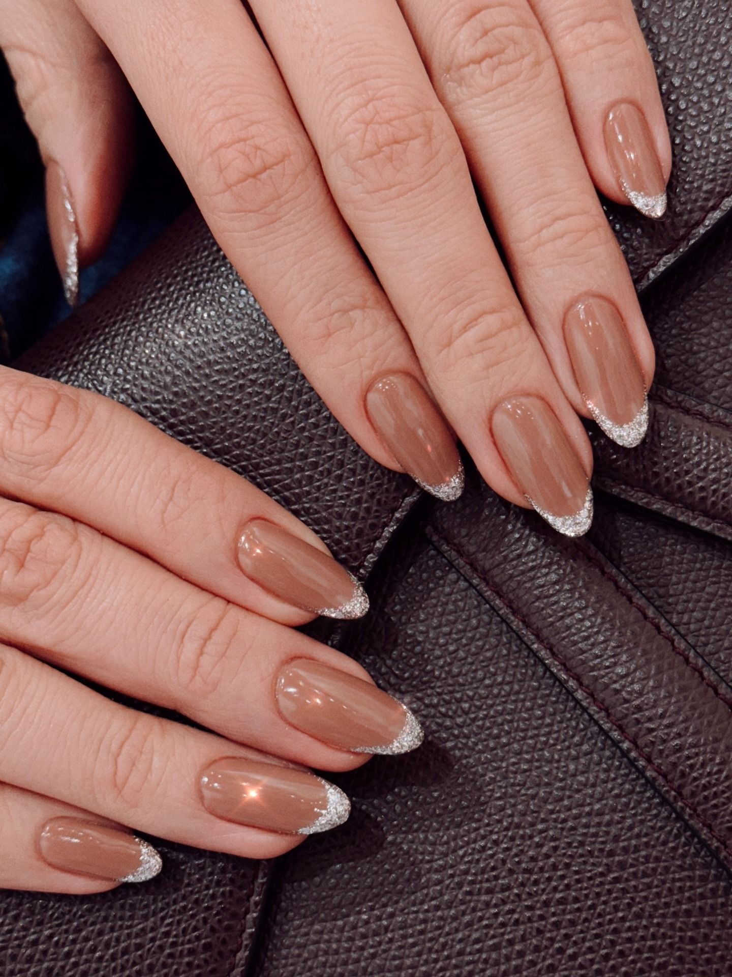 A toffee brown manicure with a glittery silver French tip