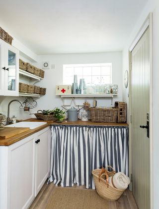 Country-style laundry room with a sink skirt and wicker baskets