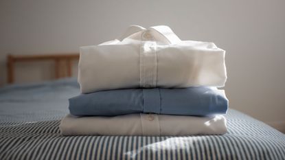 three folded shirts on bed