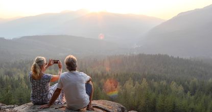 Mature couple relax on mountain ledge