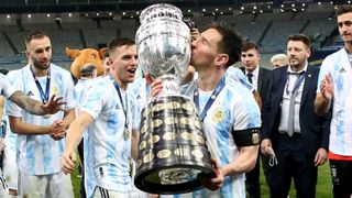 Lionel Messi kisses the Copa America with his teammates celebrating behind him