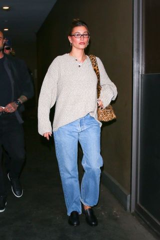 hailey bieber leaves her wedding anniversary dinner wearing a large sweater jeans and a Saint Laurent bag