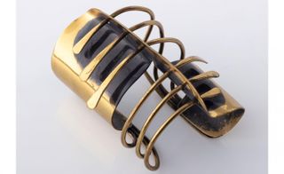 Brass spiral cuff against a grey background