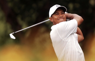 Tiger Woods wearing all white hitting an iron shot