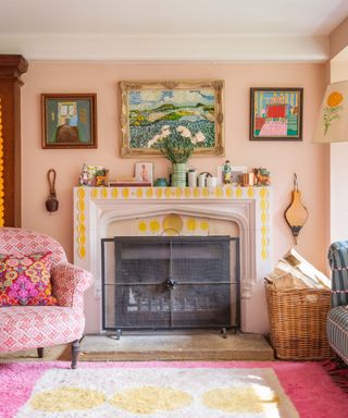 A pink living room with wall art, a fire place, a pink chair, and a pink and yellow rug