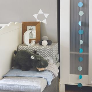 Grey painted walls with small table, white wardrobe, cuddly hippo toy and accessories