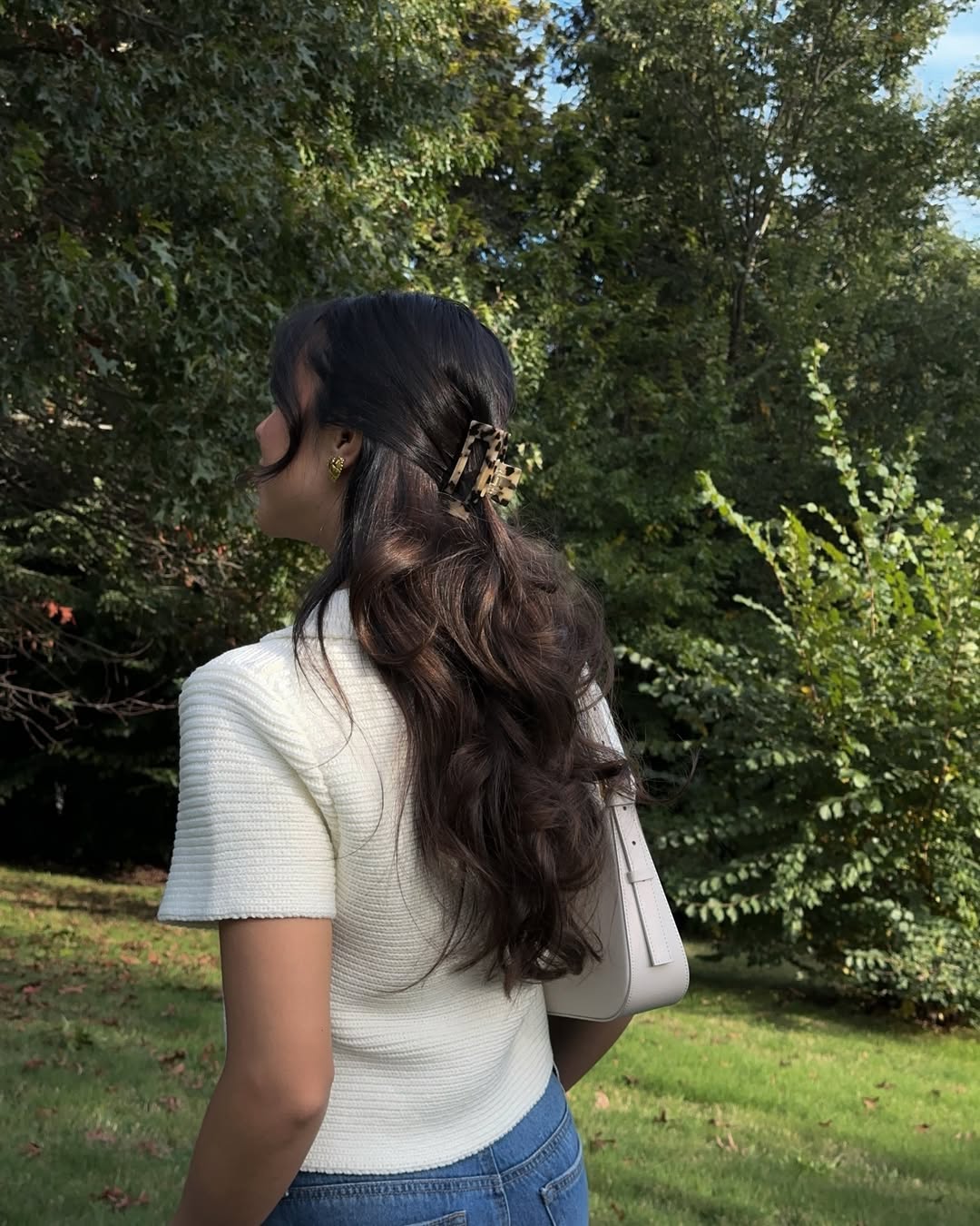 Woman with long hair and claw clip in a garden.