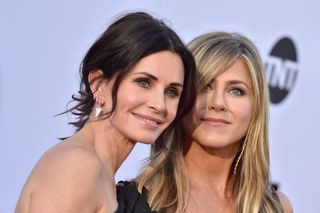 Actors Courteney Cox and Jennifer Aniston pose at a red carpet event.