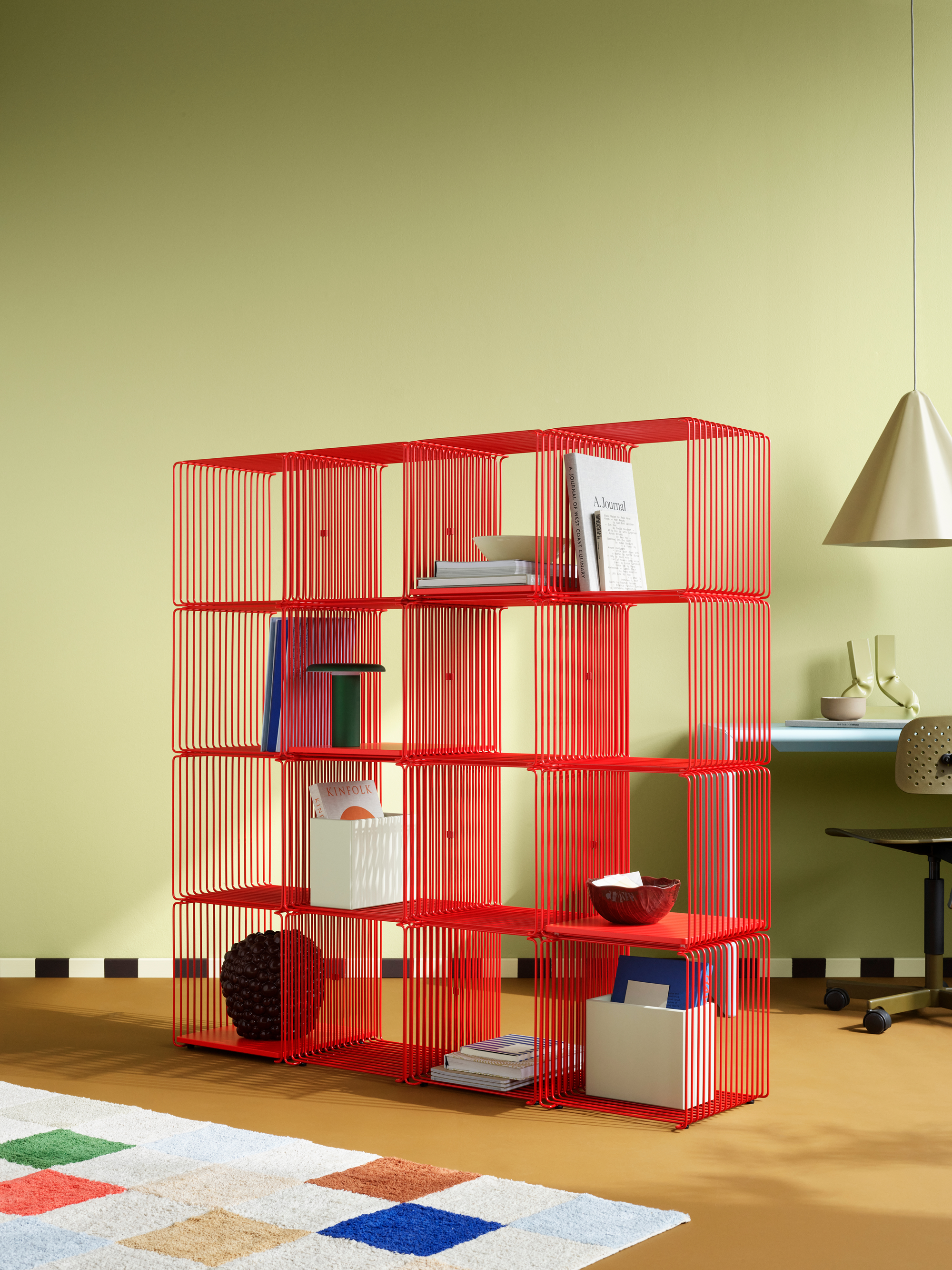 a bright red wire bookshelf in a yellow room