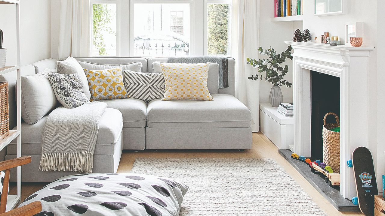 A bright white living room with a matching fireplace and a light grey corner sofa