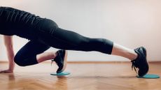 Woman doing reformer Pilates at home with core sliders