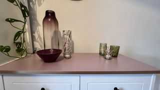 Close up of a pink painted dressing table in a small bedroom