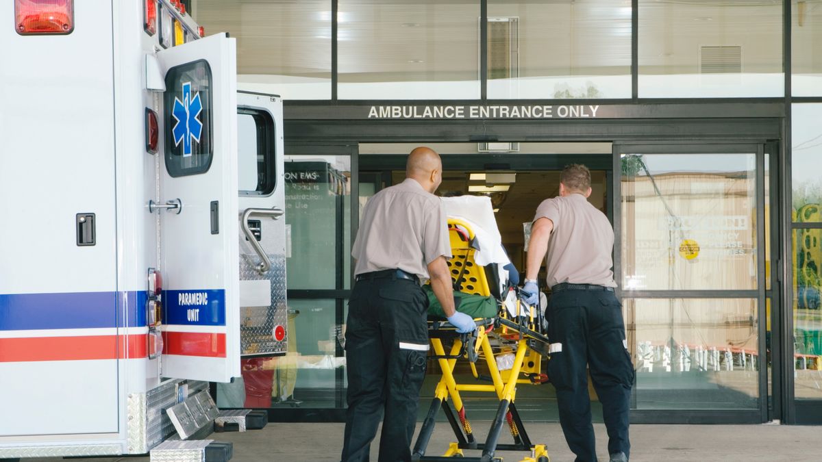 Paramedics taking patient on stretcher from an ambulance to the front door of a hospital.