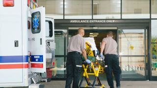 Paramedics taking patient on stretcher from ambulance to hospital.