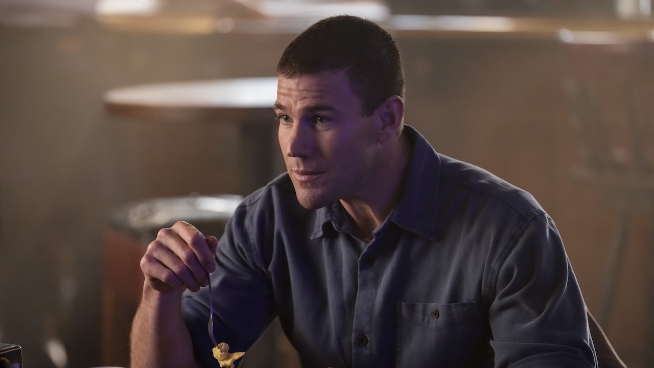 Austin Stowell&#039;s Gibbs eating food inside of a pub in NCIS: Origins