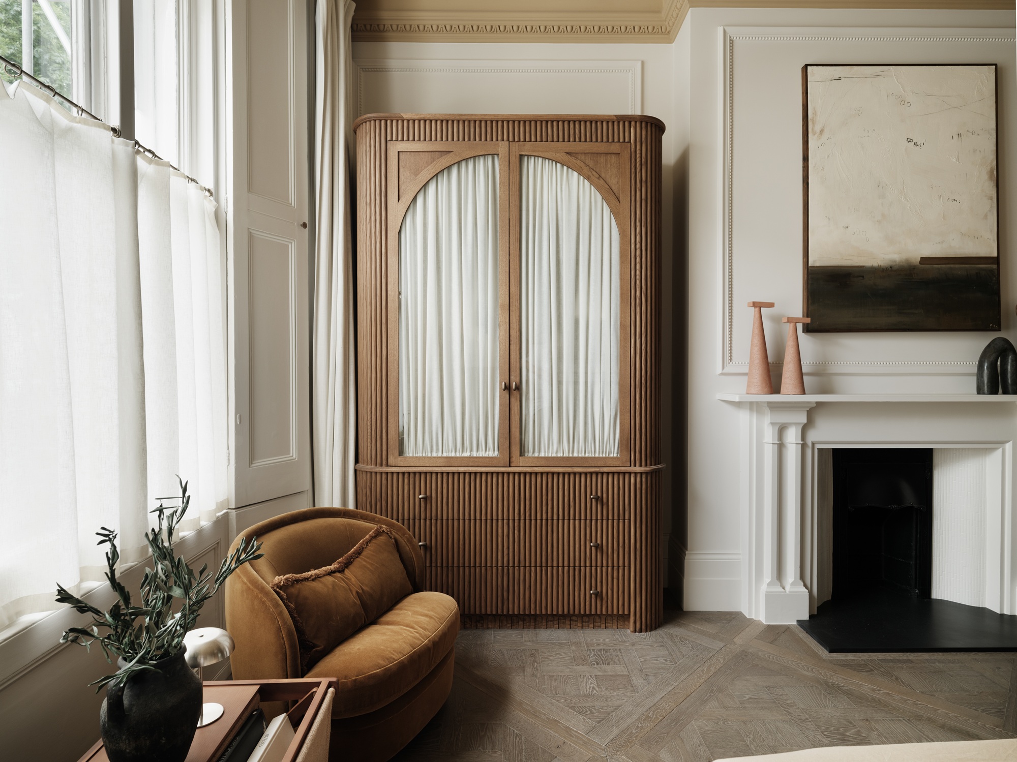 a freestanding closet in a bedroom with wooden arched doors and a curtain inside the glass