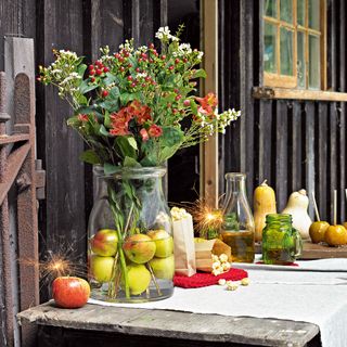 Seasonal flower and berries display on outdoor table with butternut squash