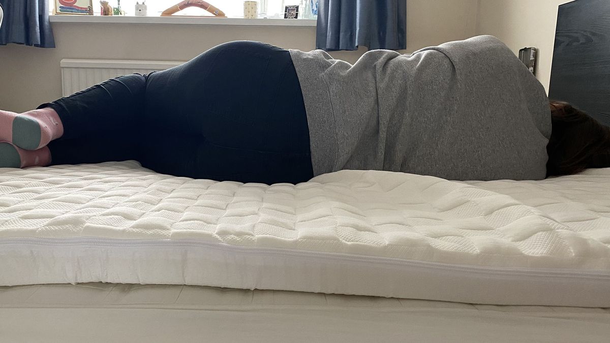 The reviewer lying in a side sleeping position on the Levitex mattress topper