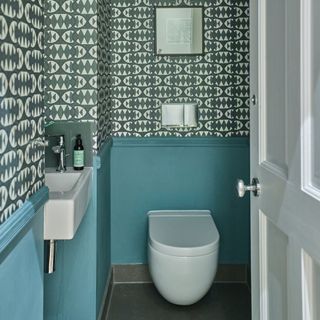 Downstairs toilet with blue panelling and a dark blue wallpaper above and a floating toilet