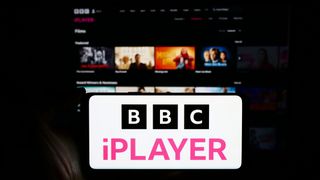 BBC iPlayer on a mobile phone with British content on a TV in the background