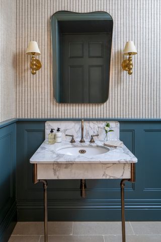 small powder room with blue painted panelling from dado rail, stripe wallpaper, marble vanity,
