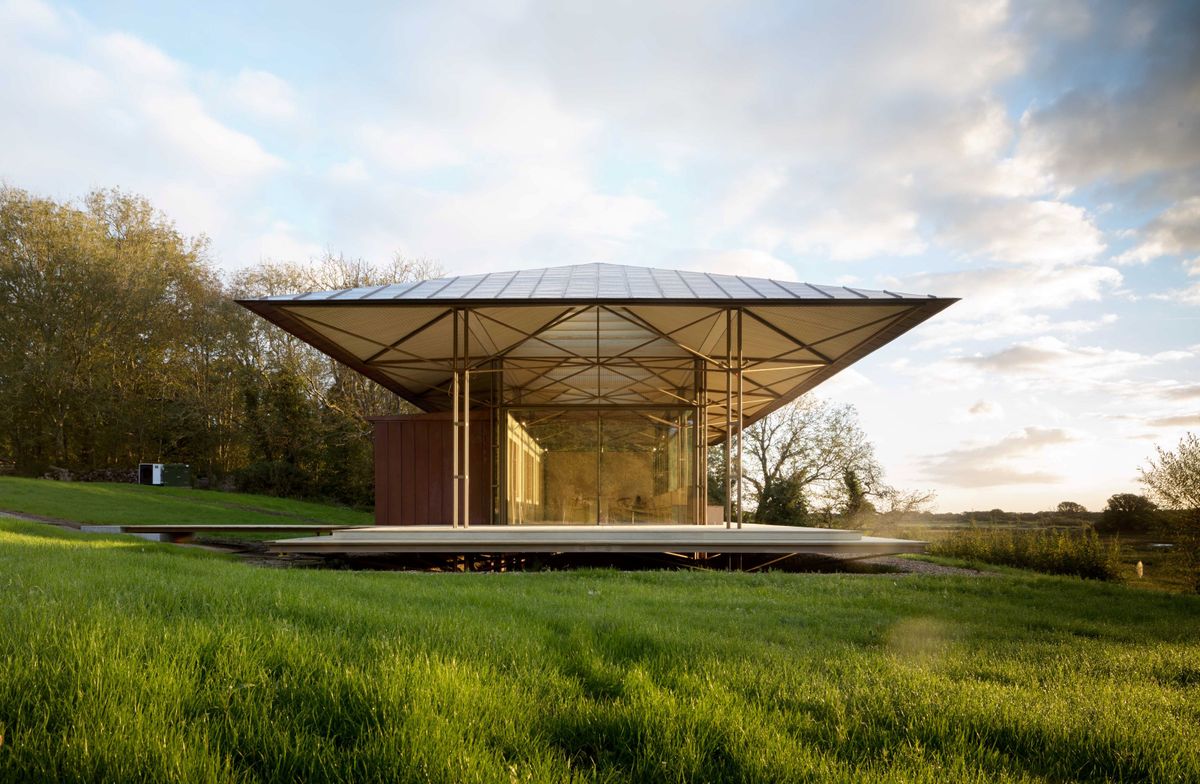 A long narrow passivhaus with a grassy and forestry surrounding with windowed walls