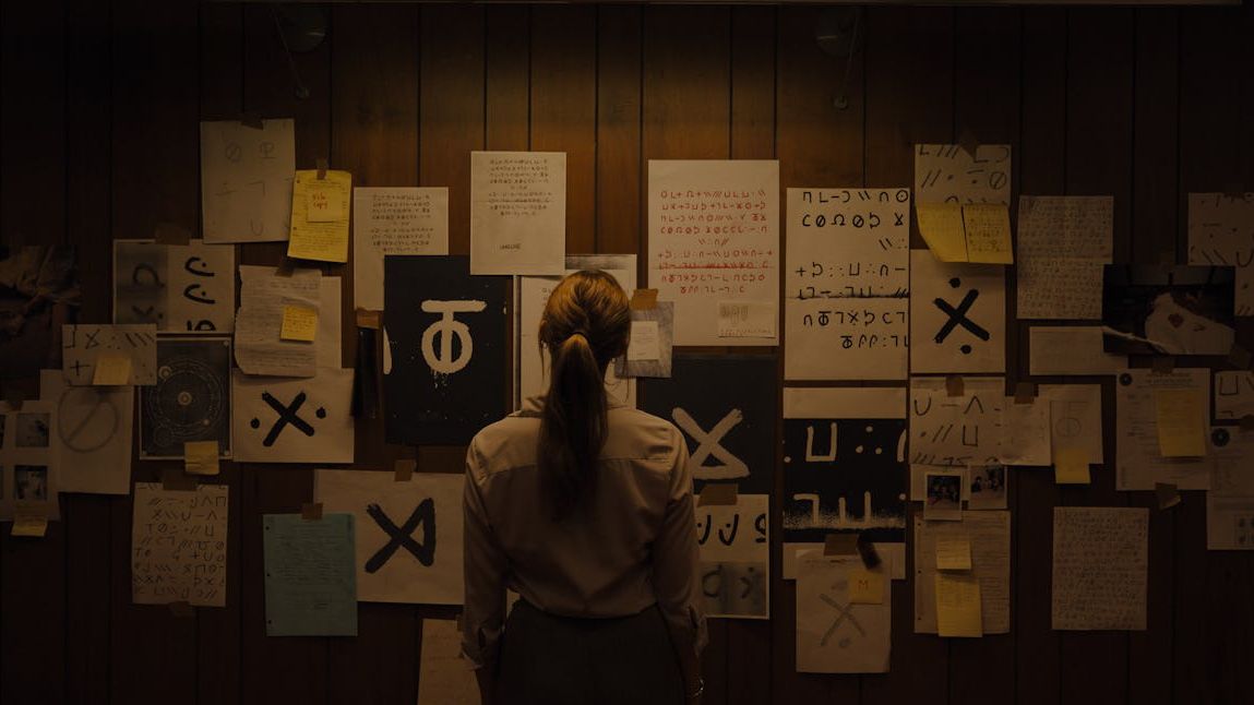 Maika Monroe as Lee Harker in front of a board of notes in Longlegs.