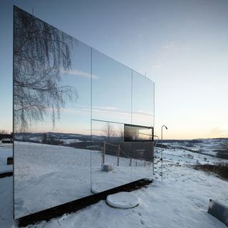 its mirrored, reflective facade helps it blend in the landscape