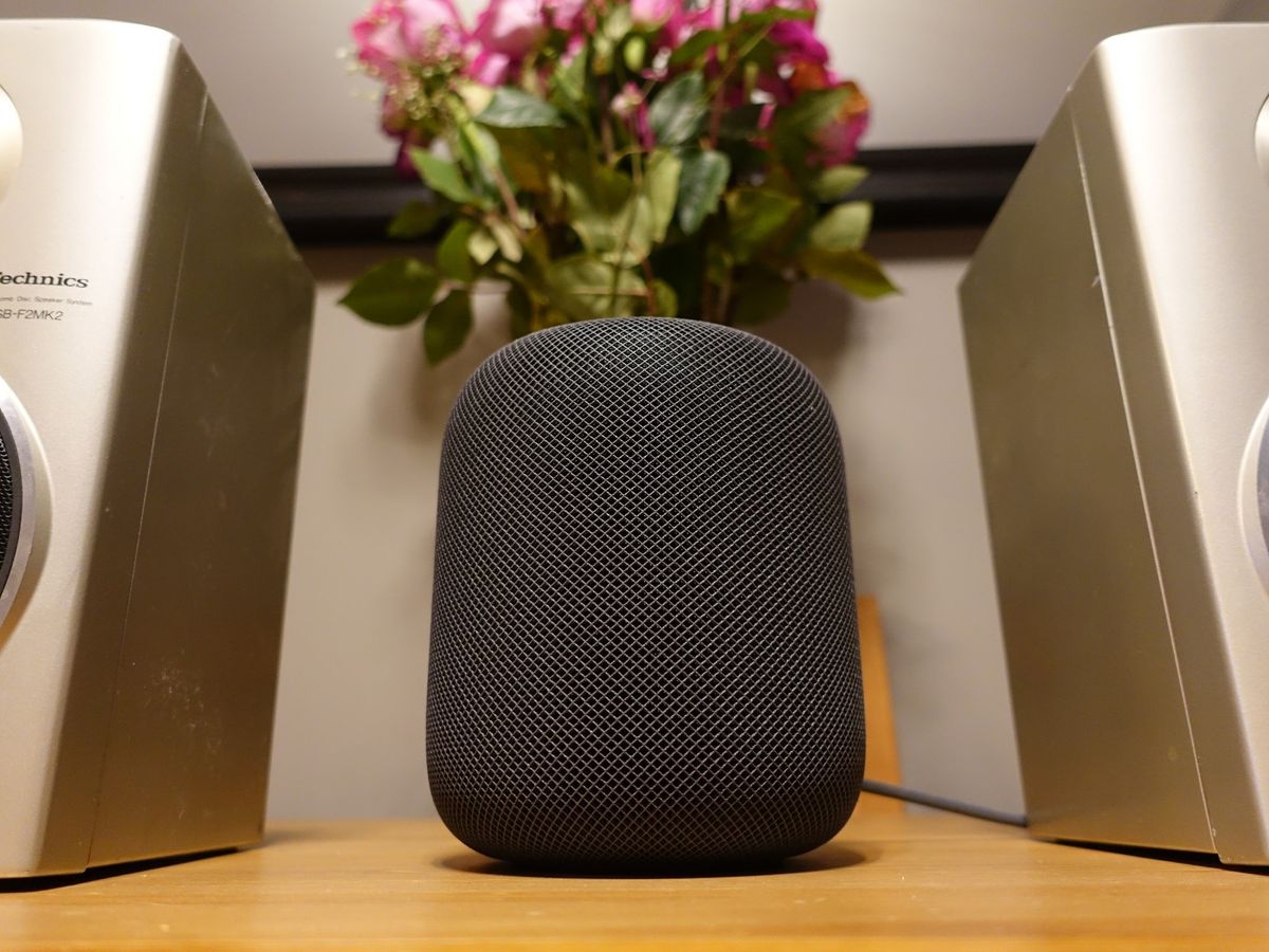 Apple HomePod in Space Gray on a table between two speakers