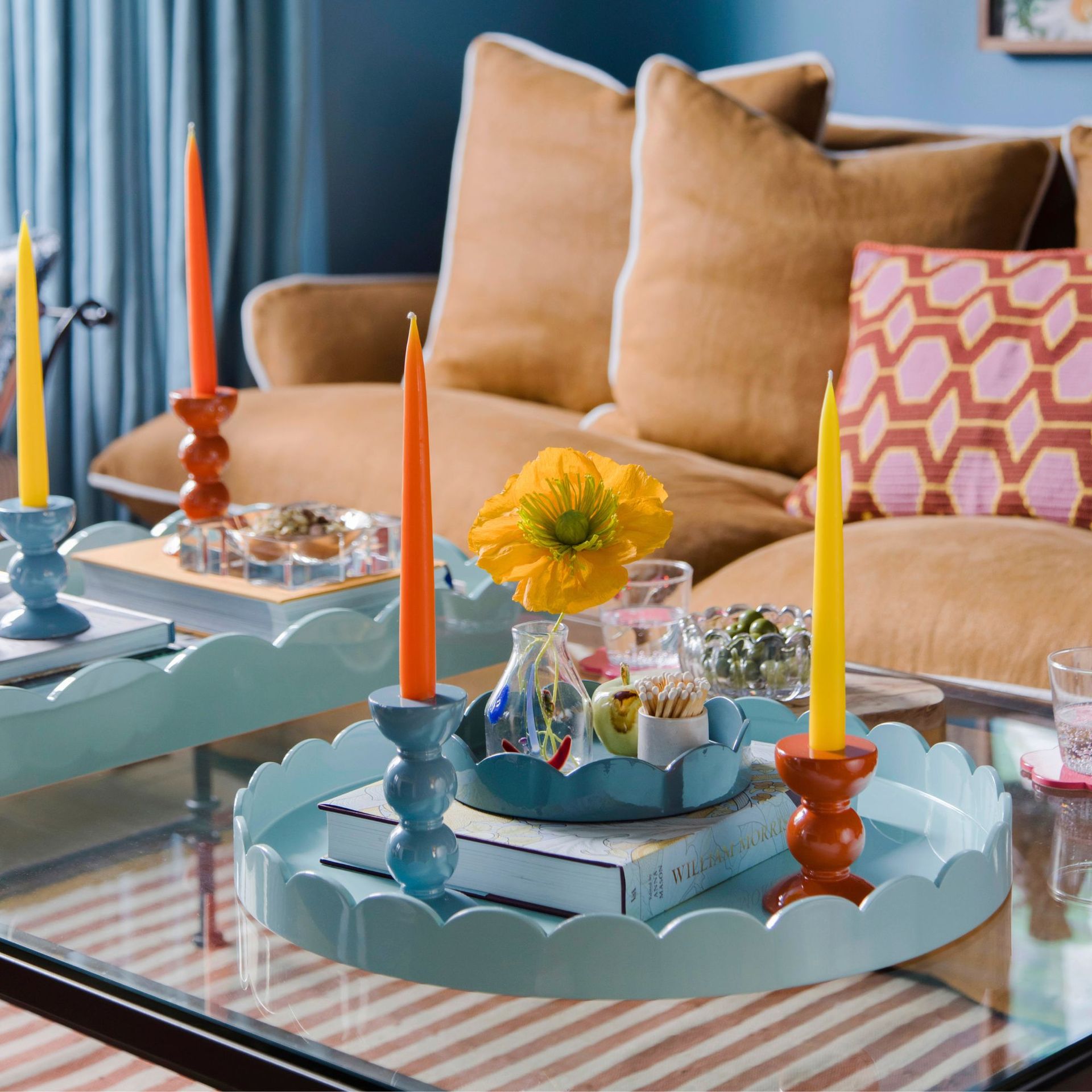 Light blue scalloped tray with decorative items displayed on top, coffee table, sofa