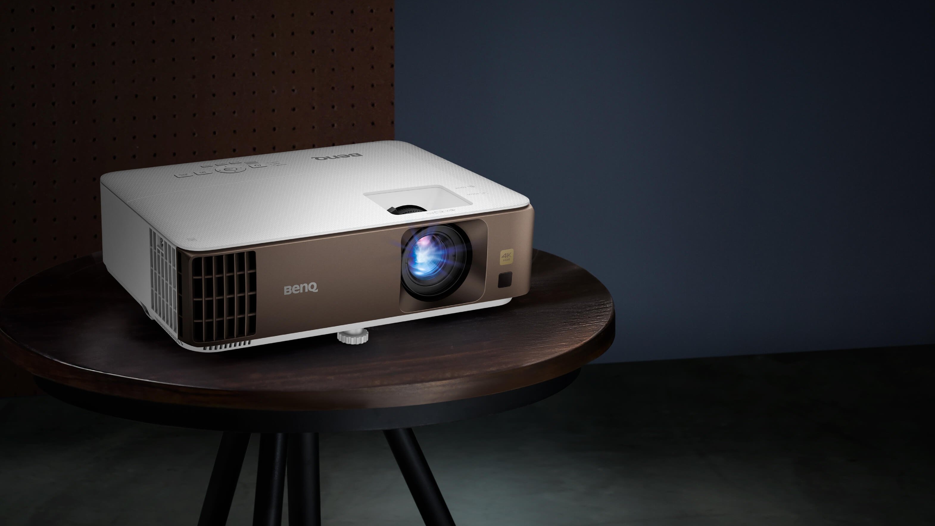 BenQ W1800 projector sitting on a circular wooden table in a dark room