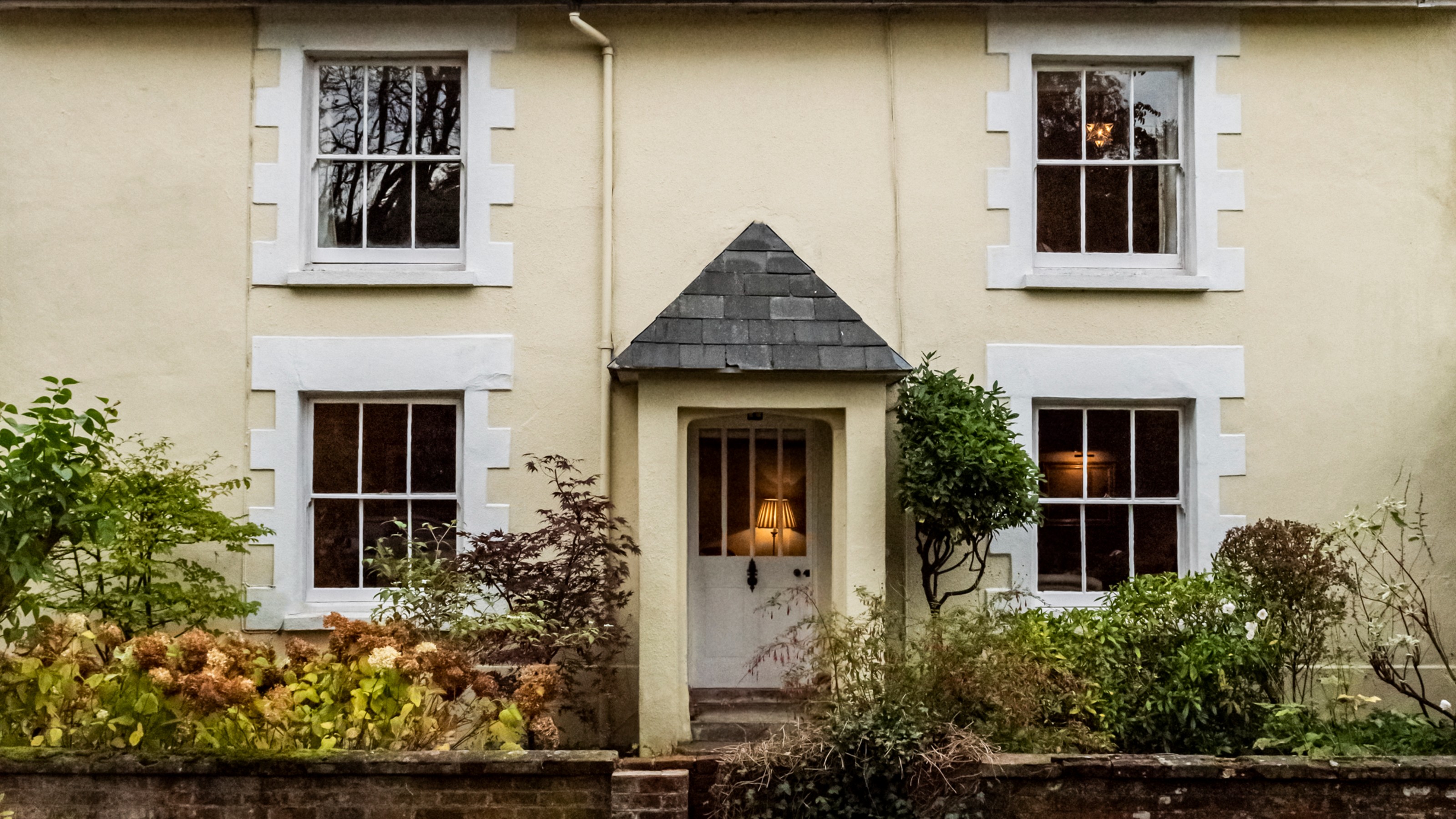 A soft yellow-painted two-storey house with white window trims and front door