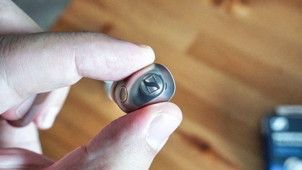Sennheiser Momentum True Wireless 5 in white, showing details of the buds held in a hand