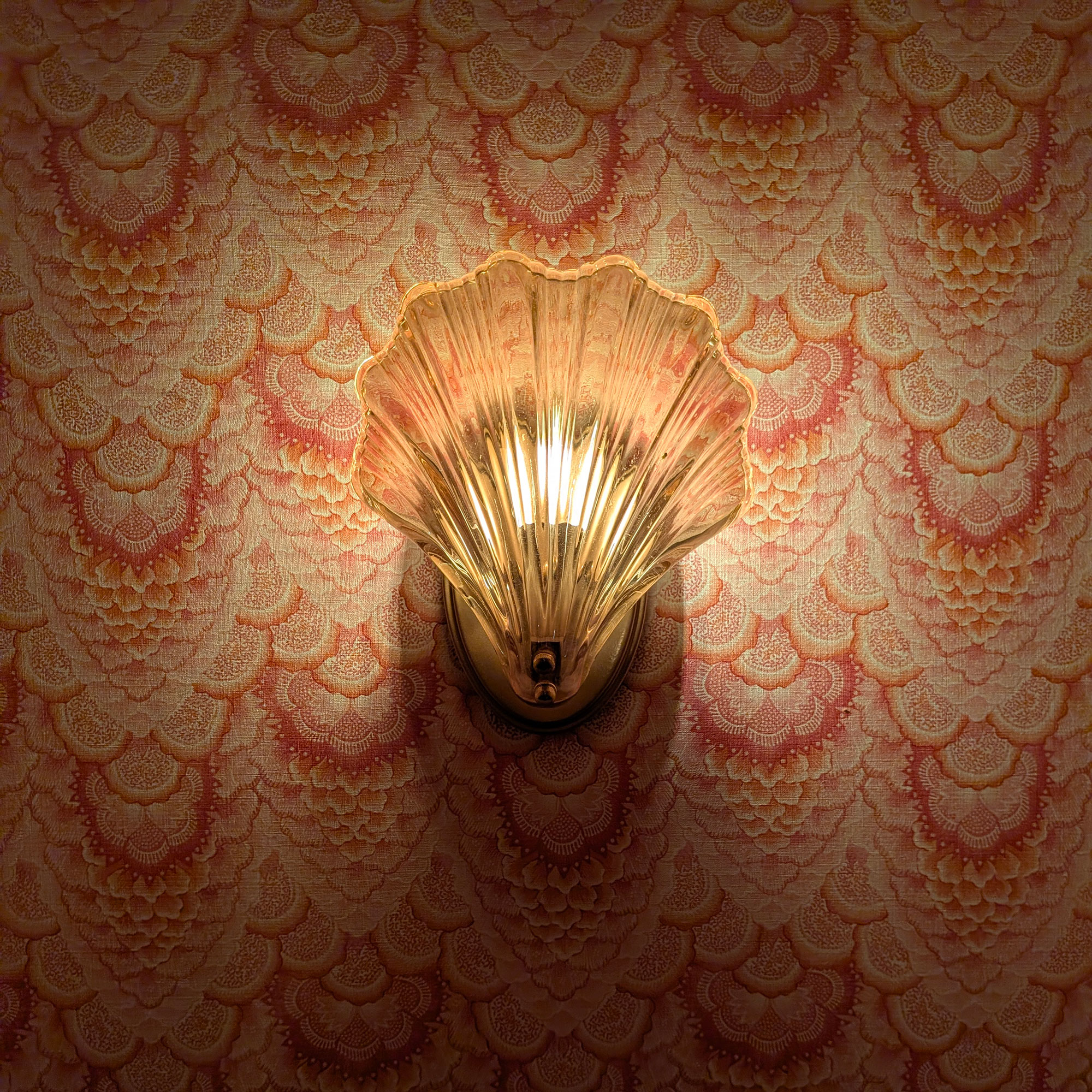 Scalloped glass scone in front of pink patterned wallpaper