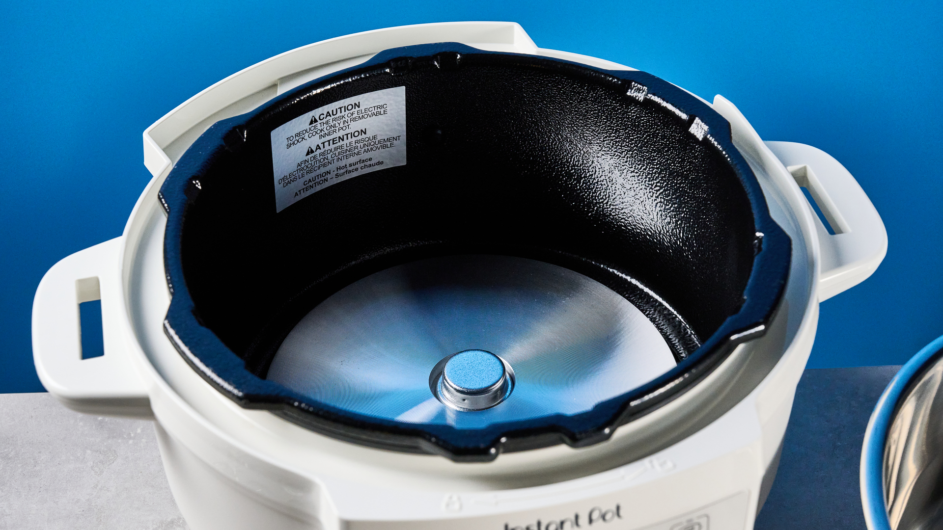 the instant pot rio mini / instant pot mini in white photographed against the blue tom's guide background showing its inner pot, accessories, and cooking programs