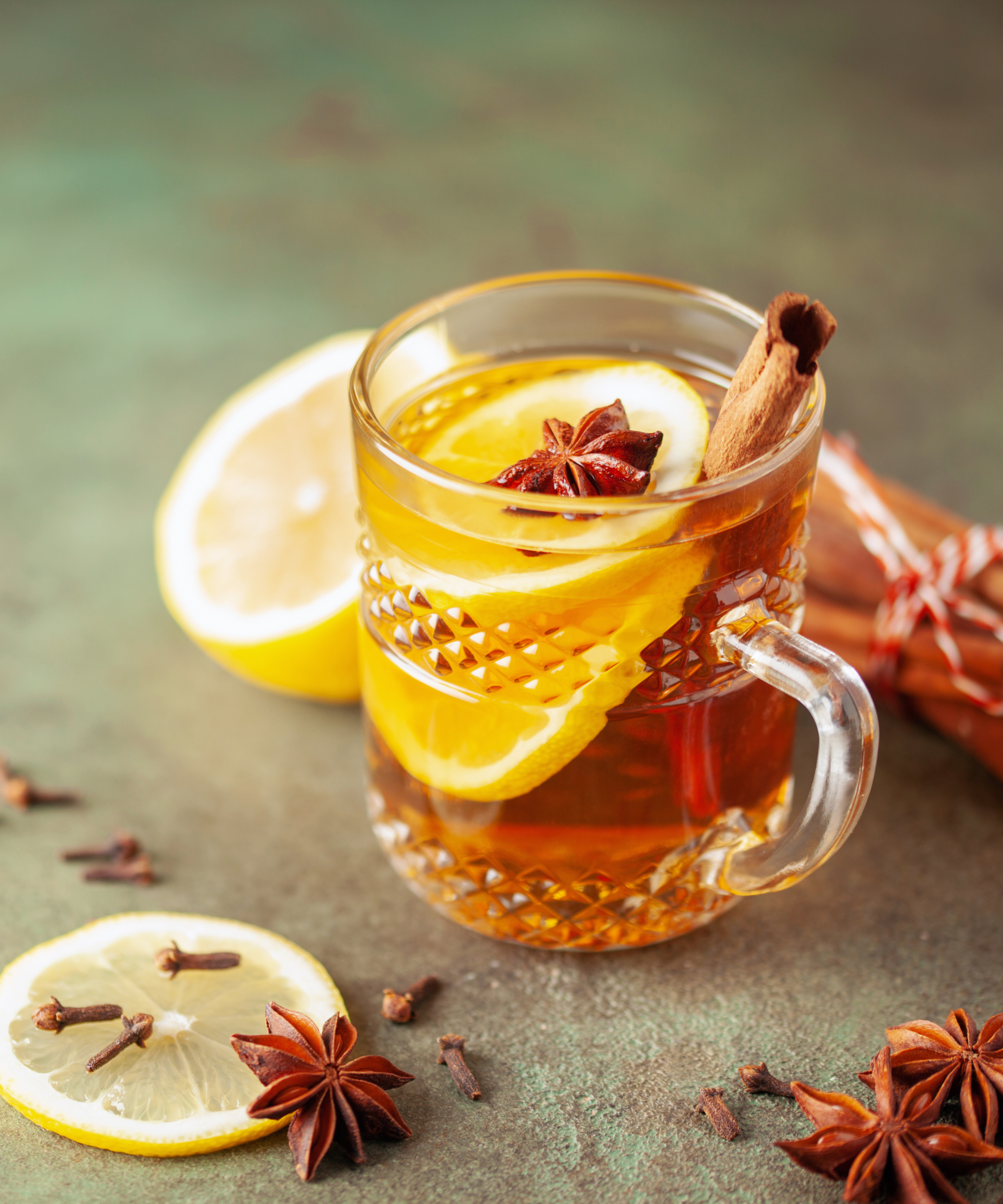 Mulled cider in a glass mug with star anise, cinnamon, and a slice of lemon