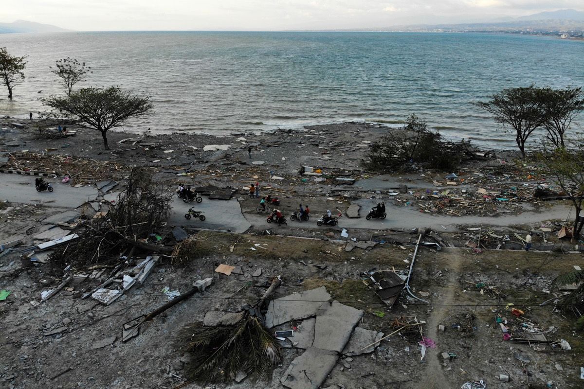 Survivors ride past debris in a devastated area in Palu, in Central Sulawesi, on Oct. 1, 2018, after a 7.5-magnitude earthquake and tsunami hit the area on Sept. 28.