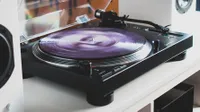 The Audio Technica AT-LP120XBT-USB record player on a white desk