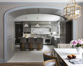 A family room area, connected to a grey kitchen through a deep arch