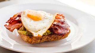 Fried egg on bacon and avocado on bread