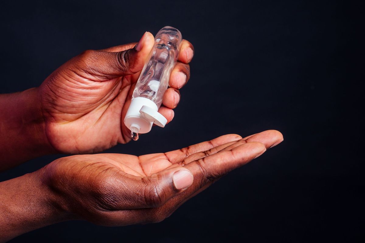 A person using a bottle of hand sanitizer.