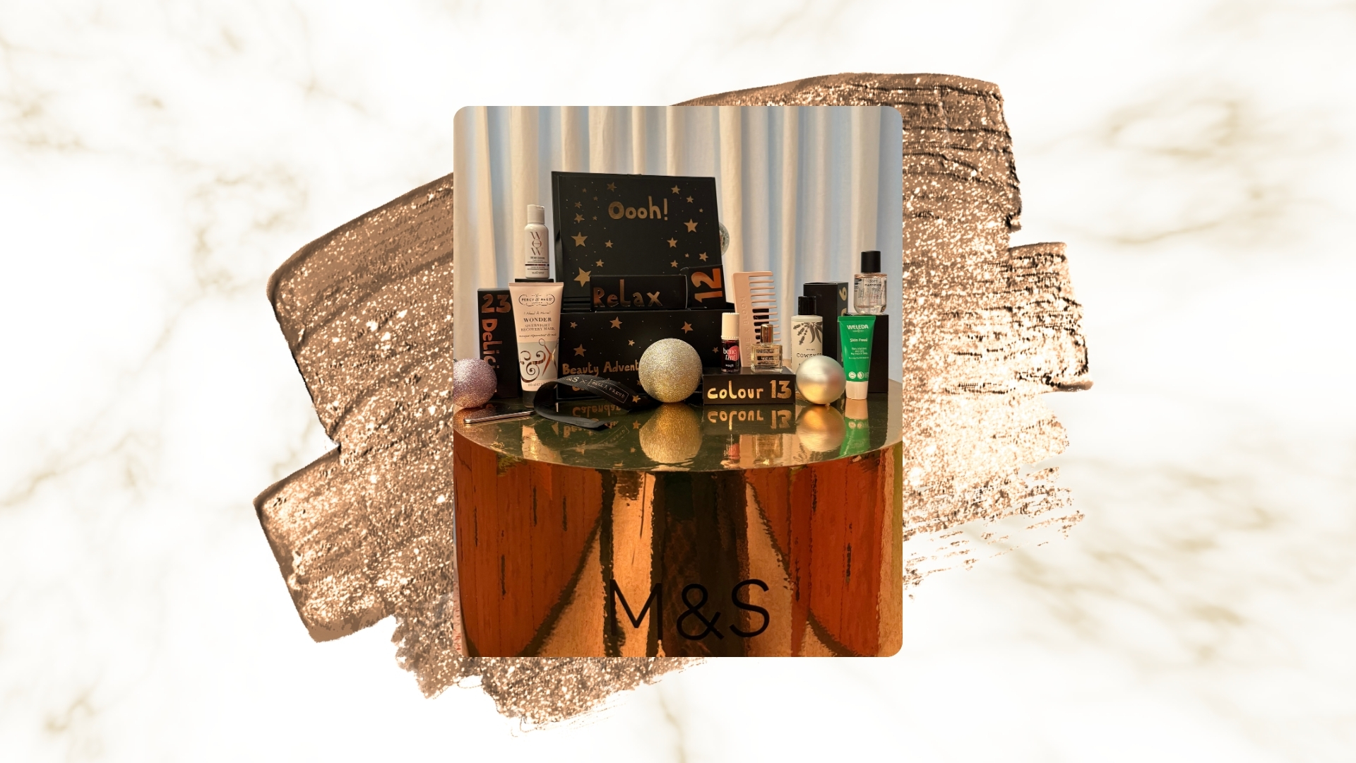 Image of M&amp;S Beauty Advent Calendar 2025 and its contents on a white and gold marble background, with a rose gold metallic swatch