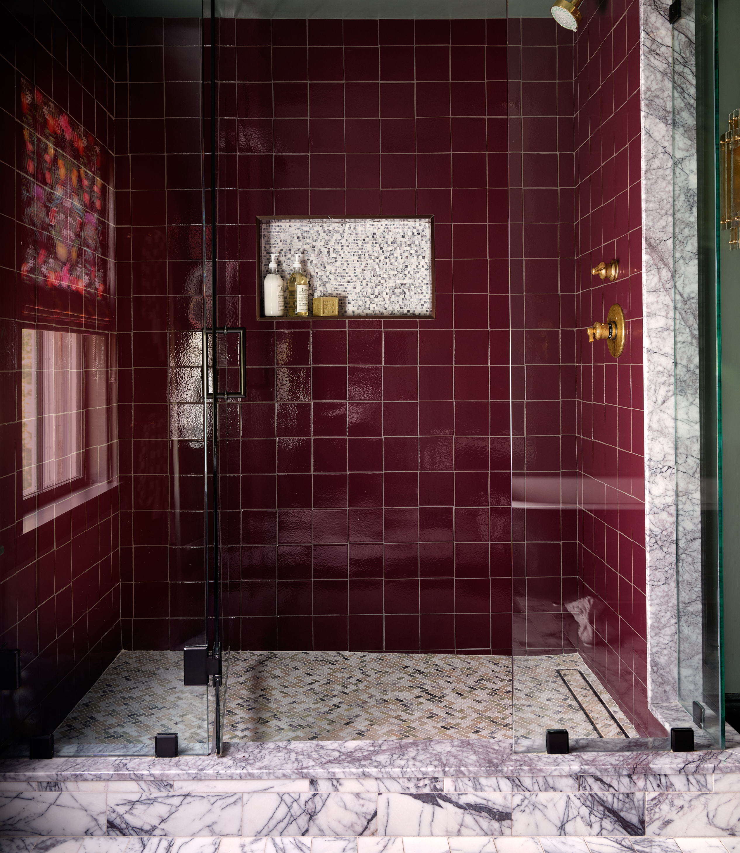 A bathroom with burgundy tiles in the shower area